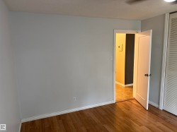Wood-finish flooring with white trim, light-toned walls, and a ceiling fan - 