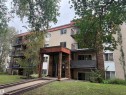 Multistory building with stucco and brick facade, multiple balconies with black railings, and a covered entrance - #205 10335 117 St Nw, Edmonton, AB 