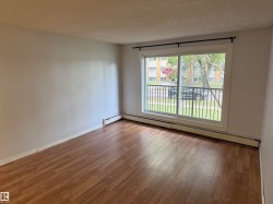 Wood-finish flooring, white painted walls, and a sliding glass door to an exterior balcony with black metal railing - 