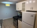 Kitchen featuring white cabinetry, glass-front upper cabinet, stainless steel range with overhead hood, and a two-door refrigerator - #205 10335 117 St Nw, Edmonton, AB 