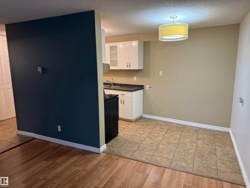 Kitchen with white cabinetry, dark countertops, and tile flooring - #205 10335 117 St Nw, Edmonton, AB 