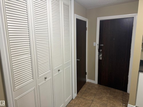 Louvered bi-fold doors, tile flooring, and dark wood-finish doors - #205 10335 117 St Nw, Edmonton, AB 