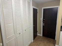 Louvered bi-fold doors, tile flooring, and dark wood-finish doors - 