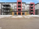 Multi-story residential building featuring a covered entryway, multiple balconies, and a paved parking area - #414 340 Windermere Rd Nw, Edmonton, AB 