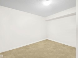 Neutral-toned carpet flooring, white walls, and a textured ceiling with flush-mount lighting - 
