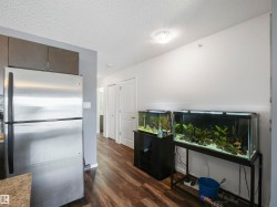 Wood-finish flooring throughout, stainless steel refrigerator, and recessed ceiling lighting - 