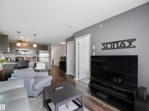 Wood-finish flooring, recessed lighting, and a modern kitchen featuring stainless steel appliances and pendant lights - #414 340 Windermere Rd Nw, Edmonton, AB 