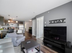 Wood-finish flooring, recessed lighting, and a modern kitchen featuring stainless steel appliances and pendant lights - 