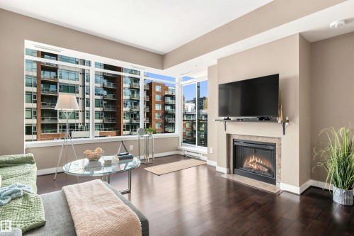Hardwood-style flooring, expansive windows, gas fireplace, and a built-in mantel shelf - #416 2510 109 St Nw, Edmonton, AB 