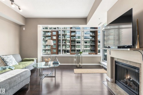 Floor-to-ceiling windows, dark wood-finish flooring, recessed lighting, track lighting, and a built-in fireplace - #416 2510 109 St Nw, Edmonton, AB 
