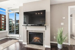 Built-in fireplace with stone surround, dark wood-finish flooring, and expansive windows - 