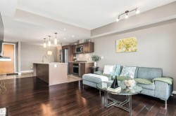 Rich wood-finish flooring, recessed lighting, track lighting, and a kitchen island with pendant lights and integrated sink - 
