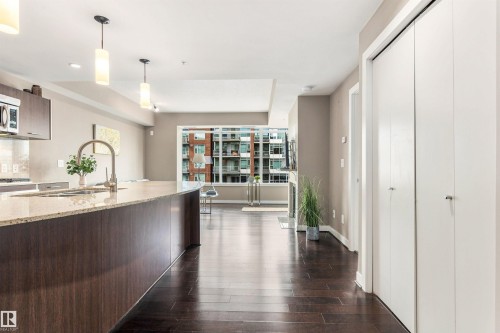 Kitchen island with light-toned countertop, stainless steel faucet, and pendant lighting - #416 2510 109 St Nw, Edmonton, AB 