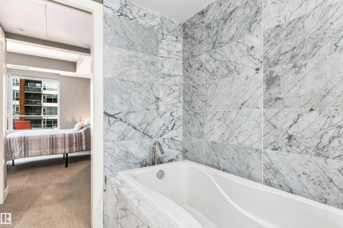 Built-in soaking tub with a deck-mounted faucet, surrounded by tiled walls - #416 2510 109 St Nw, Edmonton, AB 