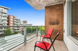 Balcony with tile flooring, glass panel railing, and brick wall accent - 