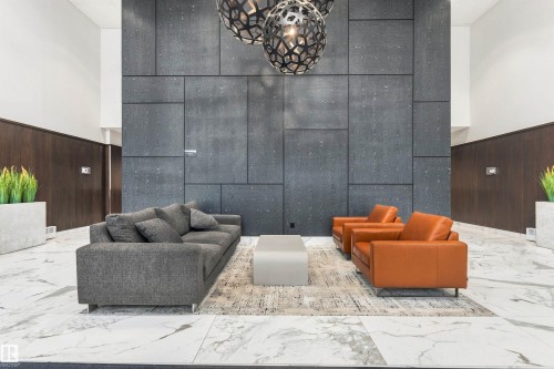 High ceilings with accent lighting, dark paneling, geometric wall panels, and white marble-style flooring - #416 2510 109 St Nw, Edmonton, AB 