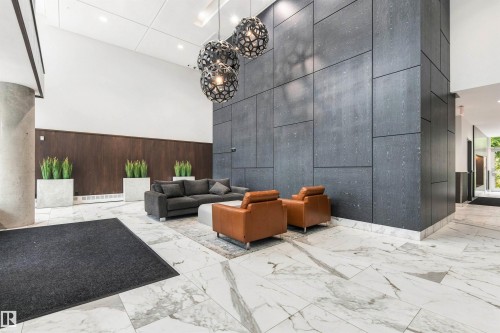 High ceilings with contemporary pendant lighting, dark wood-paneling, black accent wall, and polished marble flooring - #416 2510 109 St Nw, Edmonton, AB 