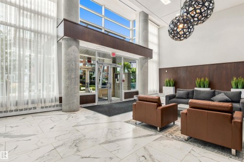 Spacious lobby featuring high ceilings, large windows with white sheer drapery, patterned pendant lighting, and marble-finish flooring - #416 2510 109 St Nw, Edmonton, AB 