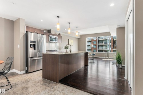 Kitchen featuring stainless steel appliances, wood-finish cabinetry, and a center island with pendant lighting - #416 2510 109 St Nw, Edmonton, AB 