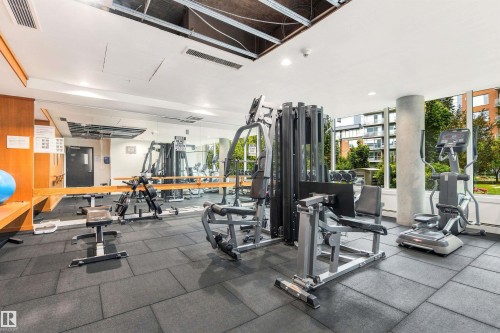 Fitness room with extensive equipment, large windows, mirrored wall, and tile flooring - #416 2510 109 St Nw, Edmonton, AB 