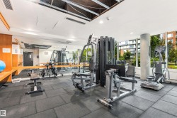 Fitness room with extensive equipment, large windows, mirrored wall, and tile flooring - 
