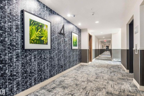 Hallway with patterned accent wall, recessed lighting, and patterned carpet flooring - #416 2510 109 St Nw, Edmonton, AB 