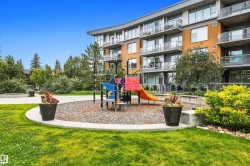 Manicured lawn with a curved concrete pathway and a colorful playground structure - 