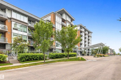 Contemporary building exterior featuring a porte-cochère, multiple balconies with metal railings, extensive glazing, and brick accents - #416 2510 109 St Nw, Edmonton, AB 