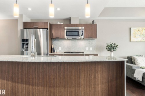 Stainless steel appliances, wood-finish cabinetry, recessed lighting, stone countertops, and a kitchen island with a sink - #416 2510 109 St Nw, Edmonton, AB 