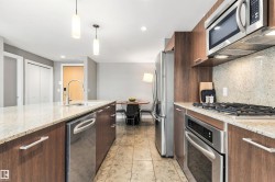 Kitchen featuring wood-finish cabinetry, stainless steel appliances, speckled countertops, and tile flooring - 