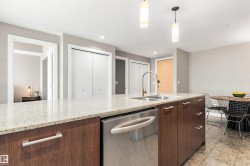 Kitchen island featuring a double basin sink, stainless steel dishwasher, and wood-finish cabinetry with silver hardware - 