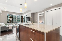 Kitchen island with a light-toned countertop, integrated double sink, and wood-finish cabinetry - 