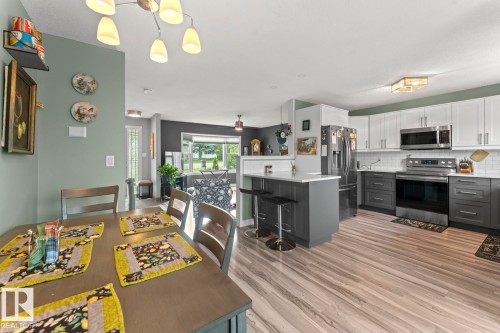 Contemporary kitchen featuring two-tone cabinetry, stainless steel appliances, white subway tile backsplash, and a central island with seating - 1303 12 Street, Cold Lake, AB 