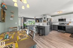 Contemporary kitchen featuring two-tone cabinetry, stainless steel appliances, white subway tile backsplash, and a central island with seating - 