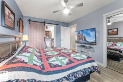 Bedroom featuring a wood-finish bed frame, light blue walls, and wood-finish flooring - 