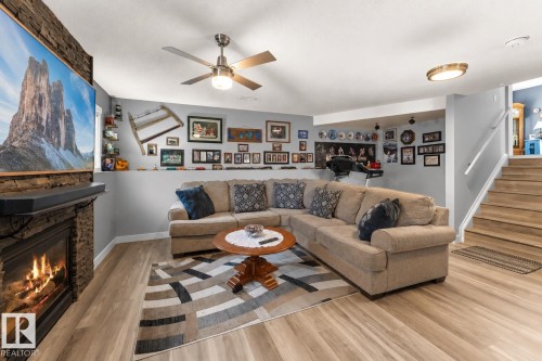 Living area featuring a stone fireplace with hearth, wood-finish flooring, and recessed lighting - 1303 12 Street, Cold Lake, AB 