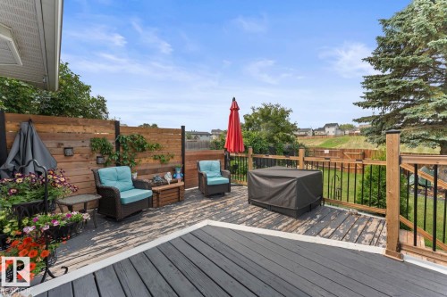 Multi-level outdoor deck featuring a dark gray composite surface, wood privacy fencing, and black metal railing with wood posts - 1303 12 Street, Cold Lake, AB 