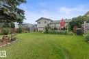 Spacious backyard featuring a large green lawn, a raised wooden deck with railings, and a wooden privacy fence - 1303 12 Street, Cold Lake, AB 