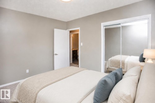 Neutral paint tones with carpet flooring and a ceiling-mounted light fixture. VIRTUALLY STAGED - #8 15431 93 Av Nw, Edmonton, AB 