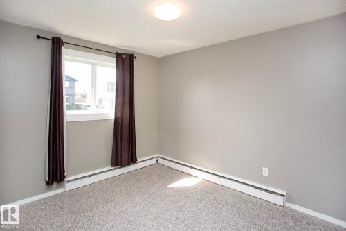 Gray wall paint, light gray carpet, white window trim, and baseboard heating - #8 15431 93 Av Nw, Edmonton, AB 