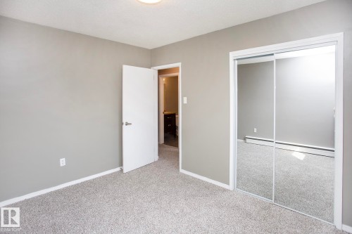 Mirrored closet doors, light gray wall paint, and gray carpeted flooring - #8 15431 93 Av Nw, Edmonton, AB 