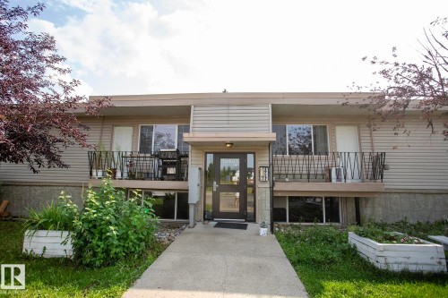 Multi-unit building featuring horizontal siding, upper-level balconies with metal railings, and ground-level windows - #8 15431 93 Av Nw, Edmonton, AB 