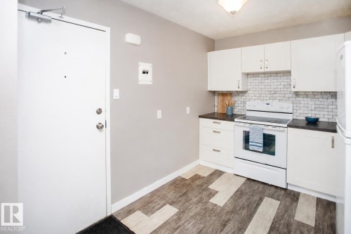 Kitchen with white cabinetry, dark countertops, a white subway tile backsplash, and an electric range - #8 15431 93 Av Nw, Edmonton, AB 
