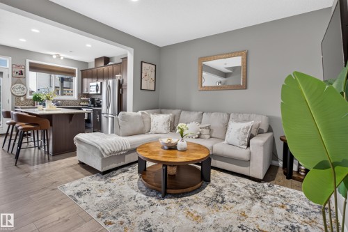 Open-concept living space with wood-finish flooring, recessed lighting, and a kitchen island featuring a breakfast bar - 1241 Mcconachie Boulevard Nw, Edmonton, AB 