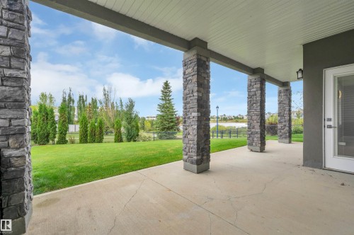 Covered patio featuring stone-clad pillars, concrete flooring, and a glass-paneled exterior door - 9054 24 Avenue Sw, Edmonton, AB 