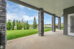 Covered patio featuring stone-clad pillars, concrete flooring, and a glass-paneled exterior door - 