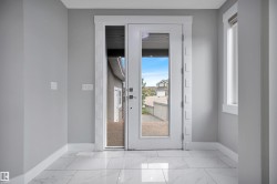 Entryway featuring large format marble-look tile flooring, a full-lite entry door, a sidelight panel, and a trim-framed window - 