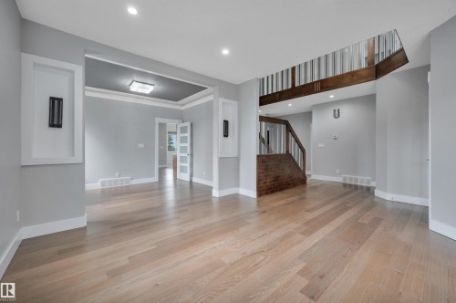Wood-finish flooring throughout, recessed lighting, and a prominent staircase with wood railing - 9054 24 Avenue Sw, Edmonton, AB 