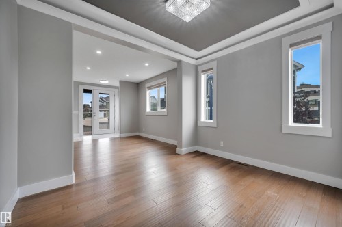 Wood-finish flooring, recessed lighting, and a coffered ceiling with a central chandelier - 9054 24 Avenue Sw, Edmonton, AB 