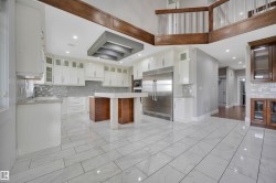 Gourmet kitchen with white cabinetry, stainless steel appliances, a central island, mosaic tile backsplash, and large format tile flooring - 